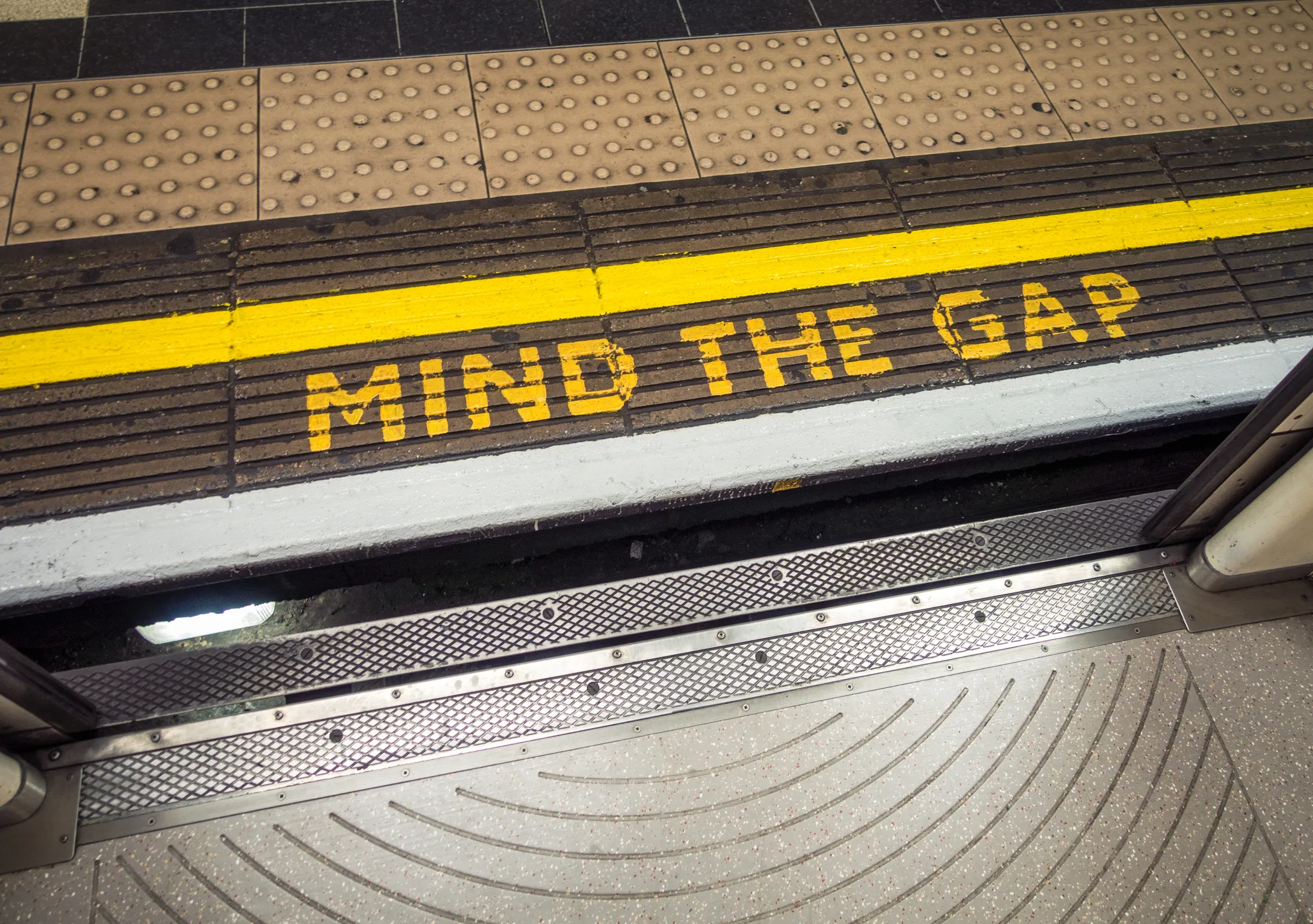 A 'Mind The Gap' warning, painted on the platform of a London Underground station.